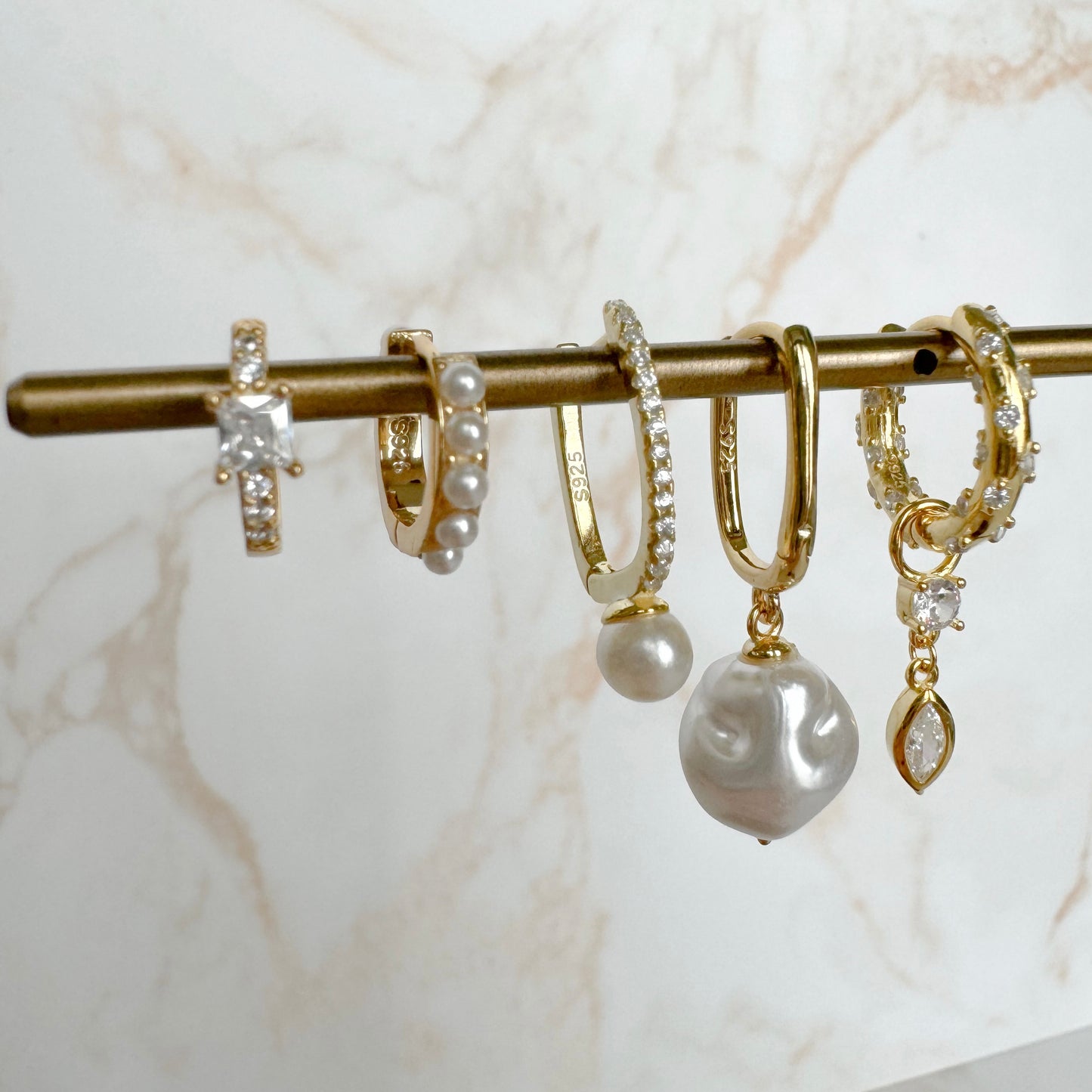 Add a touch of elegance with these must-have OVAL DROP PEARL GOLDEN HOOPS.
These hoops feature a stunning oval drop design and shimmering pearl detail.
Perfect for any occasion, elevate your style with these versatile and playful hoops.
Material: .925 Sterling Silver + 18K gold plated
Measurements: .75 x .45 in