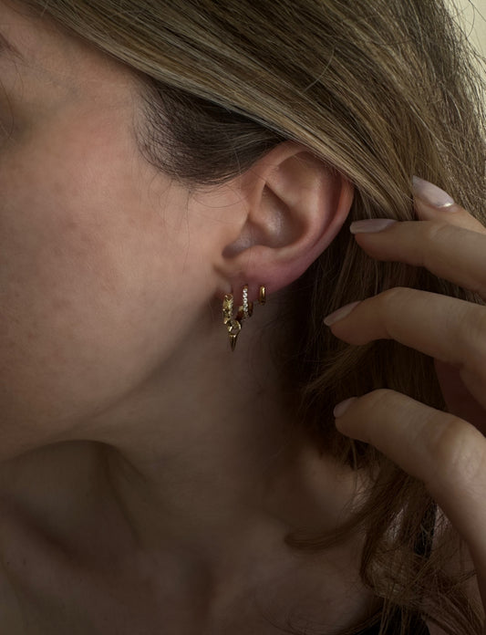 Gold spike huggie hoop earrings worn on ear